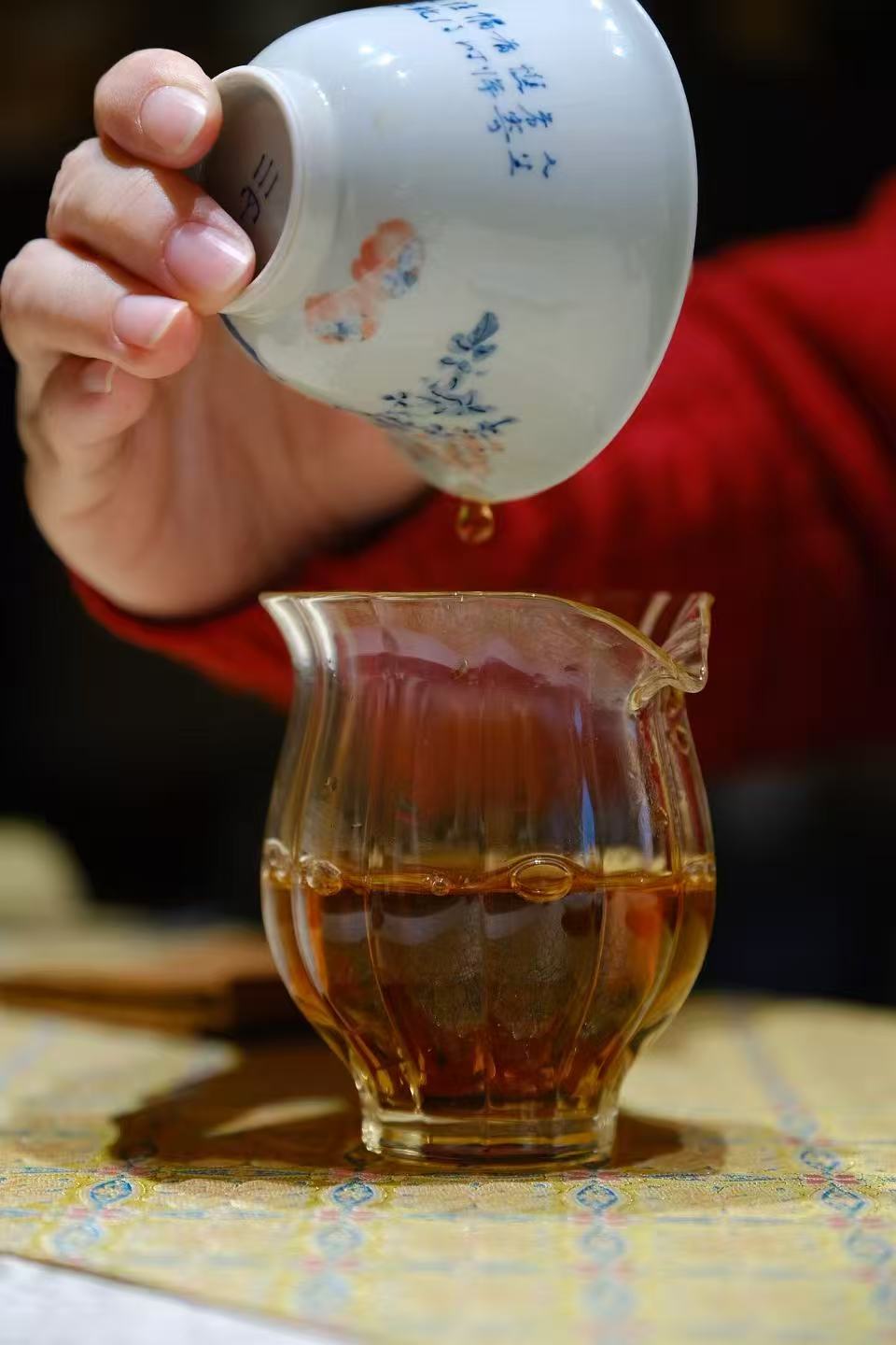 Tea being poured into a glass pitcher under warm light