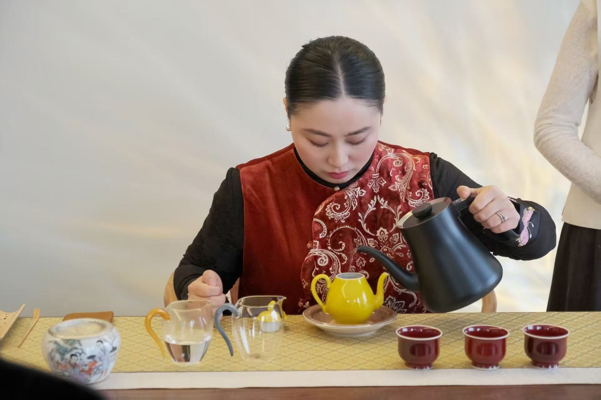 Tea host holding a glass fairness pitcher