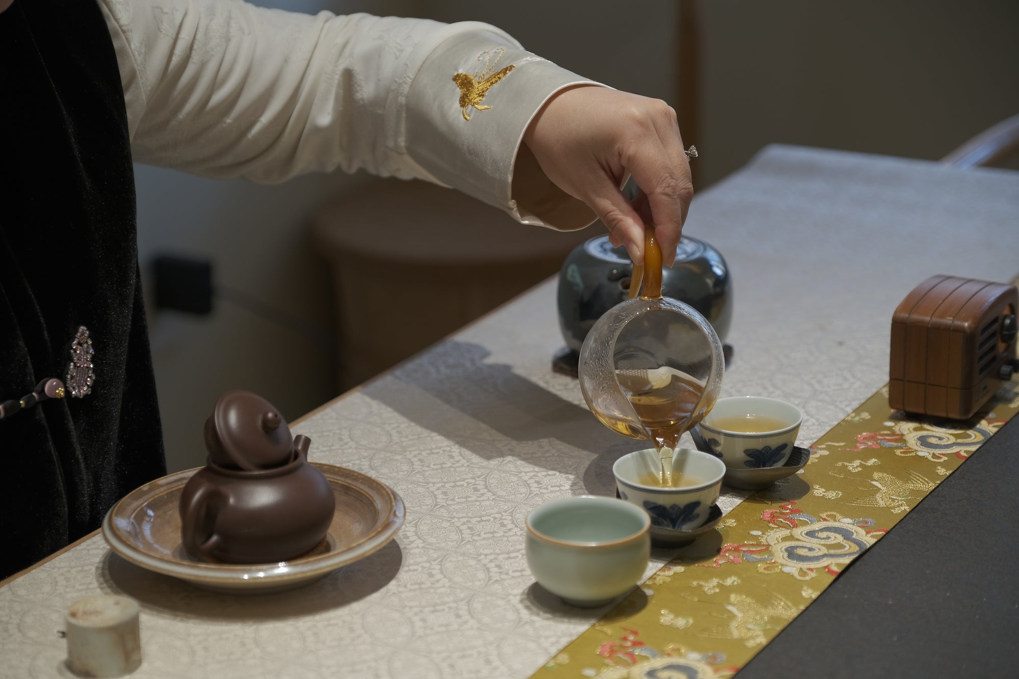 Tea host pouring tea across a prepared tea table